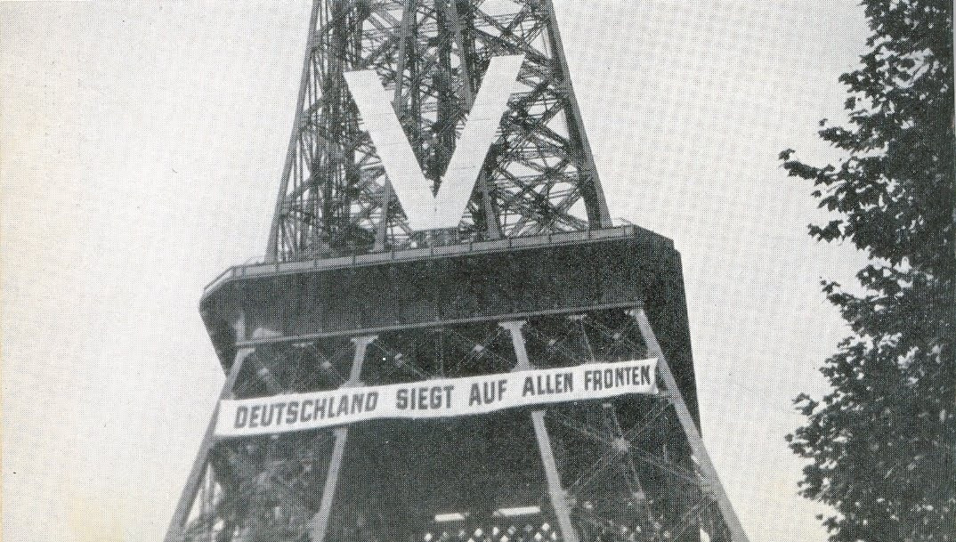 Photographie de la tour Eiffel lors de l’occupation Allemande en 1940. Nous pouvons y voir écrit « L’Allemagne est victorieuse sur tout les fronts »